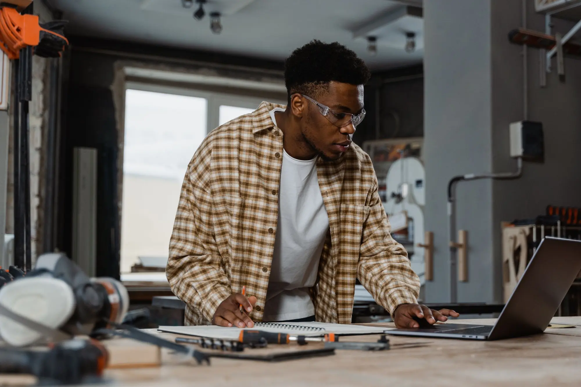 A service business owner working through quotes and scheduling on a laptop at the workbench