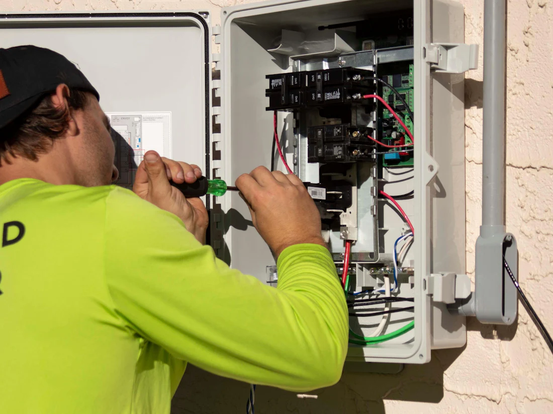 An electrician working inside a service panel