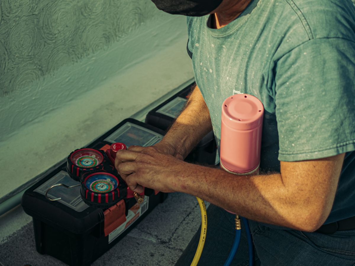 An HVAC technician checking refrigerant pressures with a manifold gauge