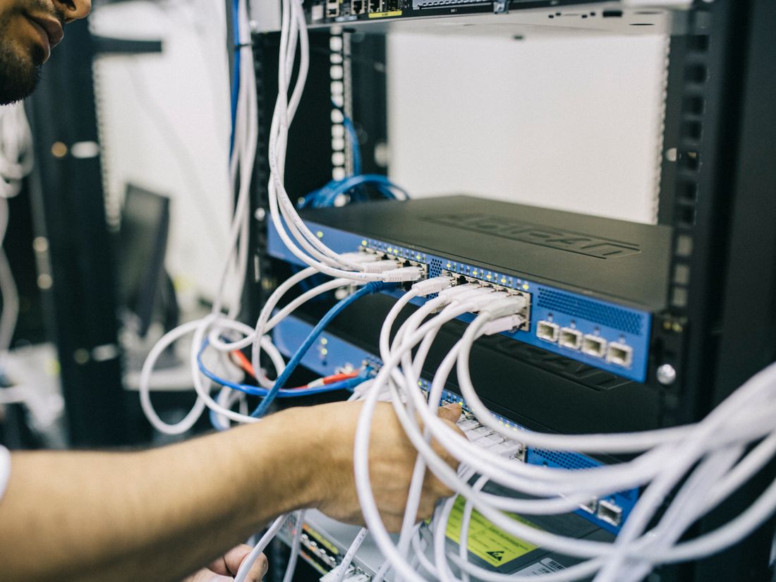 A technician patching network cables into a server rack