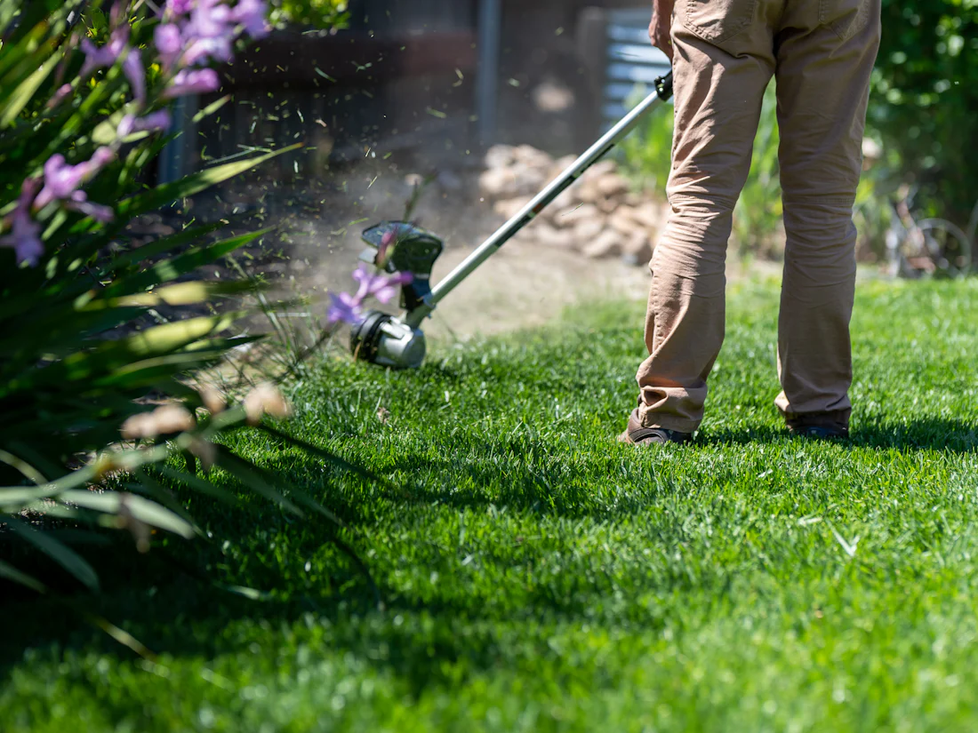 A landscaper edging a lawn with a string trimmer